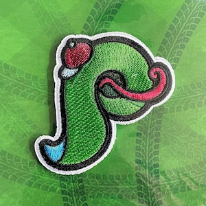 May include: Embroidered patch featuring the Phillie Phanatic "P" logo. The patch is green with black, red, white, and blue accents. The patch is on a green background with tire track designs. The packaging reads "Jawn Shop Philadelphia".