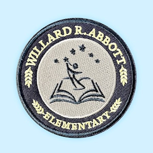 May include: Embroidered patch with the text "WILLARD R. ABBOTT ELEMENTARY" in a circular design. The patch features a central image of a person reaching for stars above an open book, with wheat stalks on either side.