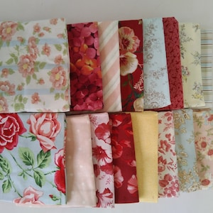 Puede incluir: Una colección de piezas de tela plegadas con estampados florales en varios colores. Las telas incluyen rosas, hortensias y otras flores en tonos rojos, rosas y amarillos. Algunas telas tienen rayas o lunares. Las telas están dispuestas sobre una superficie blanca.