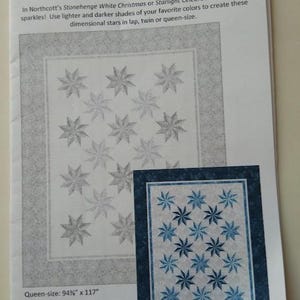 May include: A printed pattern for a quilt titled "Prism Stars" designed by Patti Carey. The pattern features star designs in shades of blue and white. The queen-size quilt measures 94.75" x 117", and the lap-size quilt measures 56.625" x 70.5".