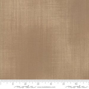 May include: A close-up of a solid brown fabric with a subtle textured pattern. The fabric is smooth and has a slightly sheen finish. The fabric is measured in inches with a ruler.