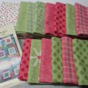 May include: A set of 20 fabric squares in shades of pink, green, and white with various patterns, including polka dots, plaid, and floral prints. The fabric squares are arranged in two rows, with a pattern booklet in the foreground. The booklet features a quilt design with a variety of blocks.