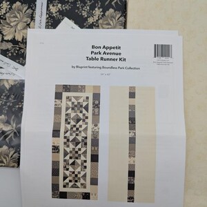 May include: A table runner kit with a floral design and the text "Bon Appetit Park Avenue Table Runner Kit" by Boundless Fabrics. The kit includes fabric and instructions for a 24 x 60 inch table runner.