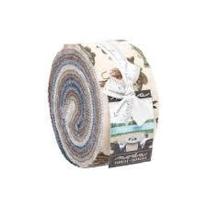 May include: A rolled bundle of patterned fabrics in shades of blue, brown, and cream, secured with a white ribbon and a tag. The fabrics are likely cotton, ideal for quilting or sewing. The roll's diameter is approximately 20 cm.
