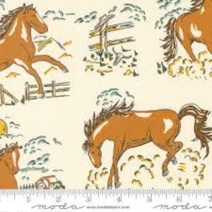 May include: A cream-colored fabric featuring a repeating pattern of brown horses, wooden fences, and farm buildings. A white ruler at the bottom shows measurements in inches, indicating the scale of the printed illustrations across the textile surface.