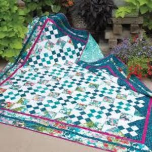 Może przedstawiać: Kołdra patchworkowa w kolorze turkusowym, białym i różowym z wzorem diamentowym. Kołdra ma szeroką obwódkę z kwiatowym nadrukiem.