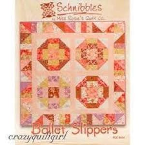 Könnte beinhalten: Ein Quiltmuster namens "Ballet Slippers" von "crazyquiltgirl" von Miss Rosie's Quilt Co. Das Muster hat einen rosa Hintergrund mit einem zentralen Quadrat, das aus vier kleineren Quadraten besteht. Jedes kleinere Quadrat hat ein anderes Design in Rosatönen, Orange und Braun.