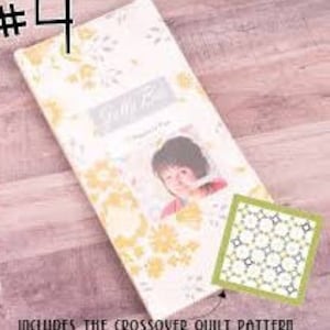 Puede incluir: Una tela floral blanca y amarilla con una foto de una niña en el centro. La tela tiene un borde de hojas grises y el texto "Stitch Fix" está impreso en la tela. Un pequeño cuadrado verde muestra un patrón repetitivo de cuadrados blancos y grises.