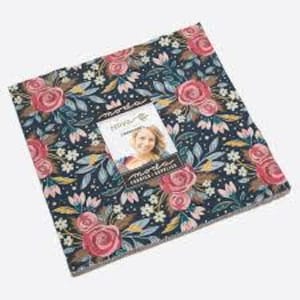 Pode incluir: Uma pilha de quadrados de tecido com um padrão floral com rosas cor-de-rosa, folhas azuis e pequenas flores brancas sobre um fundo azul marinho. Uma etiqueta com a imagem de uma mulher está no topo.