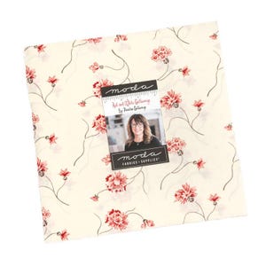 May include: A square fabric piece with a cream background, featuring a floral pattern in red and black. The fabric has a repeating design of flowers and vines. A label with the text "Red and White Gatherings" and a woman's photo is attached.