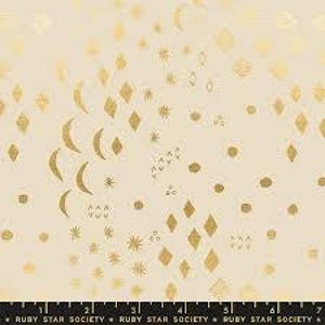 Może przedstawiać: Kremowa tkanina z powtarzającym się wzorem złotych kształtów niebieskich, w tym księżyców, gwiazd, diamentów i kropek. Tkanina ma metaliczny połysk. Linijka na dole obrazu pokazuje wymiary w centymetrach.