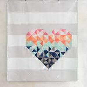 May include: A geometric heart quilt with a gradient of pink, orange, blue, and gray colors. The heart is on a white background with gray stripes.