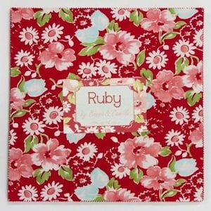 May include: A red fabric square with a floral pattern in shades of pink, white, and green. The fabric has a label that says "Ruby by Moda Fabrics".