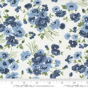 Könnte beinhalten: Ein weißer Baumwollstoff mit einem sich wiederholenden Blumenmuster aus dunkelblauen und hellblauen Blüten mit grünen Blättern und Stielen. Am unteren Rand ist ein Lineal sichtbar, das Maße in Zoll zur Skalierung und Größenreferenz zeigt.