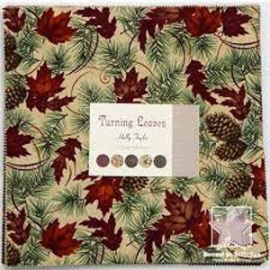 Puede incluir: Un panel de tela con un patrón repetido de hojas de arce rojas, ramas de pino y piñas sobre un fondo beige. El panel está etiquetado como "Turning Leaves" por Holly Taylor.