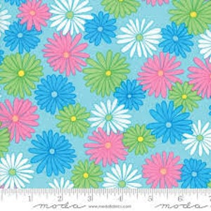 May include: A repeating pattern of colourful daisies in pink, blue, green, and white on a light blue background. The daisies have yellow centres. A ruler is at the bottom of the image.