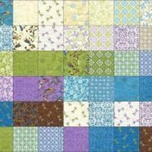 Op de afbeelding: Een patchworkquilt met vierkanten van stoffen met patronen in blauw, groen, paars en crème. De ontwerpen omvatten libellen, bloemmotieven en geometrische patronen. De quilt toont een mix van texturen en kleuren.