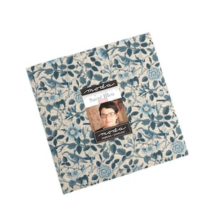 May include: A square piece of fabric featuring a blue and cream floral and bird design. The fabric has a label with the text "Sacré Bleu" and a woman's image. The fabric is from Moda Fabrics + Supplies.