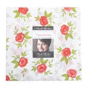 Könnte beinhalten: Ein quadratisches Stoffpaneel mit einem Blumenmuster aus roten Rosen, grünen Blättern und kleinen weißen Blüten auf weißem Hintergrund. Das Panel enthält ein zentrales Bild mit Text und einem Frauenporträt sowie das Moda Fabrics-Logo.