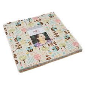 May include: A stack of fabric squares with a repeating pattern of houses, trees, and figures in pastel colors. A central rectangular opening reveals a woman's portrait. The fabric has a cream background.