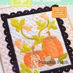 Puede incluir: Un tapiz de pared acolchado que presenta un parche de calabaza con dos calabazas naranjas, enredaderas verdes y flores amarillas. El título "Pumpkin Patch" está cosido en hilo marrón en la parte inferior del diseño. El diseño está enmarcado con un borde negro festoneado.