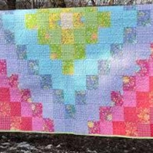 May include: A colorful patchwork quilt with a gradient design. The quilt features squares of fabric in shades of red, pink, orange, yellow, green, blue, and purple. The quilt is approximately 60 inches wide and 70 inches long.