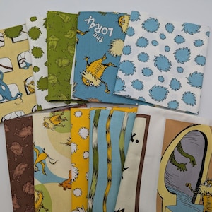 May include: A selection of folded fabric squares featuring Dr. Seuss-themed designs. The patterns include characters, text from "The Lorax", and whimsical illustrations in yellow, green, blue, and brown. The fabrics are arranged on a white surface.