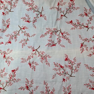 May include: A light blue fabric with a repeating pattern of red cardinals perched on brown branches with red berries.