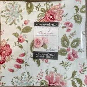 Puede incluir: Un paquete de tela cuadrado con un estampado floral en tonos rosa, rojo y verde sobre un fondo blanco. El paquete incluye una etiqueta que dice "Moda Porcelain" con una imagen de rosas rosas. La tela es probablemente para acolchar o manualidades.