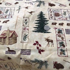 May include: Beige fabric with a repeating pattern of woodland animals, cabins, and pine trees. The fabric features a brown moose, a brown cabin, a green pine tree, and a brown bear.