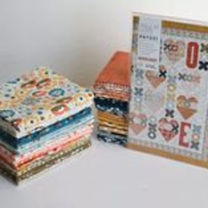 以下が含まれることがあります： ハートと「LOVE」の文字が描かれたキルトのパターンが入ったキルトキット。キットには、青、オレンジ、黄色、緑の様々な色合いの花柄と幾何学模様のファブリックスクエアが含まれています。