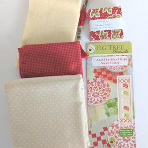Peut inclure: Un ensemble de tissus crème, rouges et blancs, avec du fil à broder rouge et un paquet intitulé "Christmas Figs". Les tissus présentent des motifs unis, à pois et à motifs, pour un projet de couture ou de patchwork. Le paquet indique "...And The Stockings Were Hung."