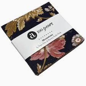 May include: A stack of fabric squares with a floral pattern in shades of navy, gold, and pink. A white band wrapped around the squares displays the text "100 years" and "Moonstone". The fabric is likely for quilting or other sewing projects.