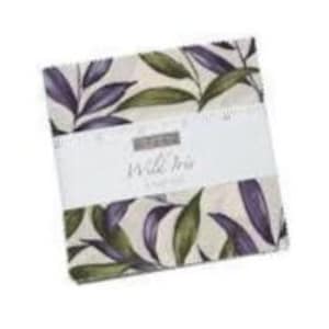 May include: A square stack of fabric squares featuring a botanical print of purple and green leaves on a cream background. A white paper band wraps around the centre, printed with the text Wild Iris and a 5-inch ruler scale along the top edge.