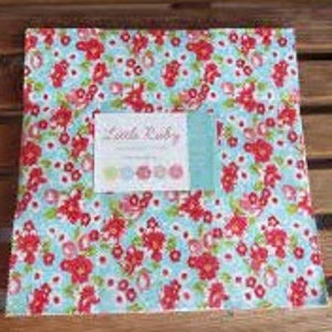 May include: A square fabric bundle with a floral pattern of red flowers and green leaves on a light blue background. The fabric bundle has a white label with the text "Little Ruby" and colorful circles.