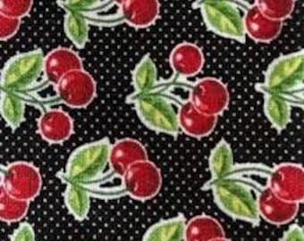 May include: Black fabric with a repeating pattern of red cherries with green leaves on white stems. The background is black with white polka dots.