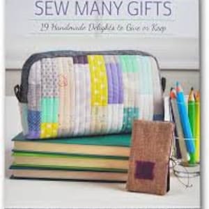 Puede incluir: Un libro titulado "Sew Many Gifts: 19 Handmade Delights to Give or Keep" que presenta una bolsa de cosméticos de tela de patchwork colorida y una pequeña bolsa de tela marrón.