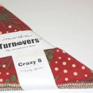 May include: A stack of red and green Crazy 8 fabric squares, wrapped with a white band that reads "Turnovers" and "Crazy 8". The fabric has a pattern of white polka dots and green leaves.