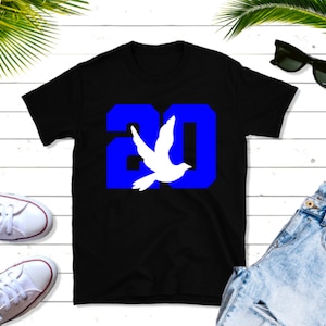 May include: Black t-shirt with a blue number "20" and a white dove graphic.