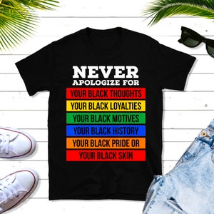 Puede incluir: Camiseta negra con el texto "NEVER APOLOGIZE FOR" en letras blancas y una gama de colores arcoíris con el texto "YOUR BLACK THOUGHTS", "YOUR BLACK LOYALTIES", "YOUR BLACK MOTIVES", "YOUR BLACK HISTORY", "YOUR BLACK PRIDE OR", "YOUR BLACK SKIN" en letras blancas.