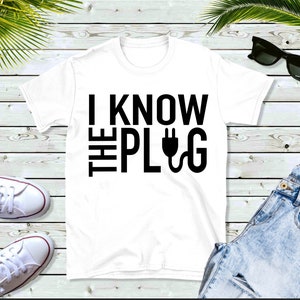 May include: White t-shirt with black text that reads "I know the plug" with a plug symbol.
