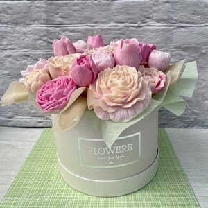 Puede incluir: Un ramo de flores de jab&oacute;n rosa y blanco dispuestas en una caja blanca con el texto "FLOWERS just for you".
