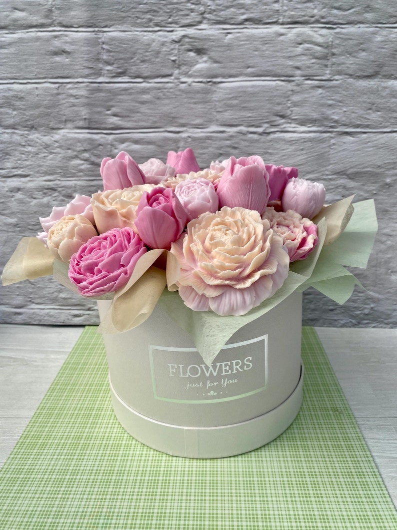 Puede incluir: Un ramo de flores de jab&oacute;n rosa y blanco dispuestas en una caja blanca con el texto "FLOWERS just for you".