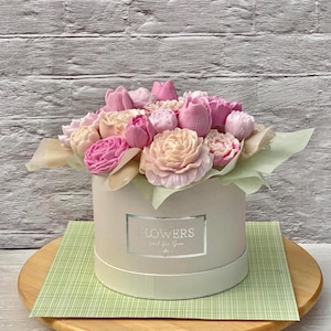 Puede incluir: Una caja blanca con una cinta rosa y un ramo de flores de jab&oacute;n rosas y melocot&oacute;n. La caja tiene una etiqueta plateada que dice "Flowers Just for You".