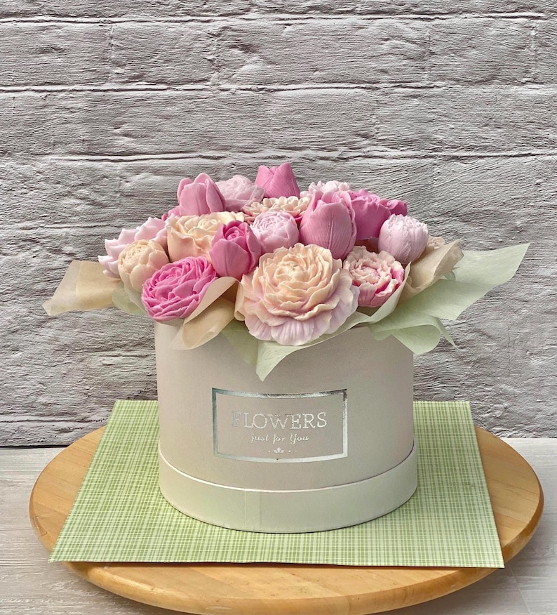Puede incluir: Una caja blanca con una cinta rosa y un ramo de flores de jab&oacute;n rosas y melocot&oacute;n. La caja tiene una etiqueta plateada que dice "Flowers Just for You".