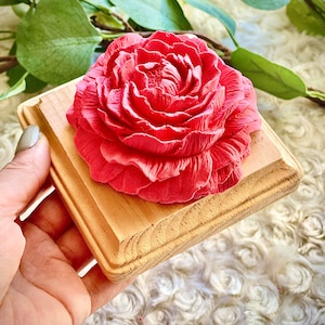May include: A bright pink rose flower crafted from resin is displayed on a small wooden square base. The base has a natural wood grain finish.