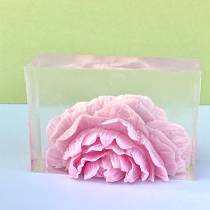 May include: A pink flower soap encased in a clear rectangular block of soap.