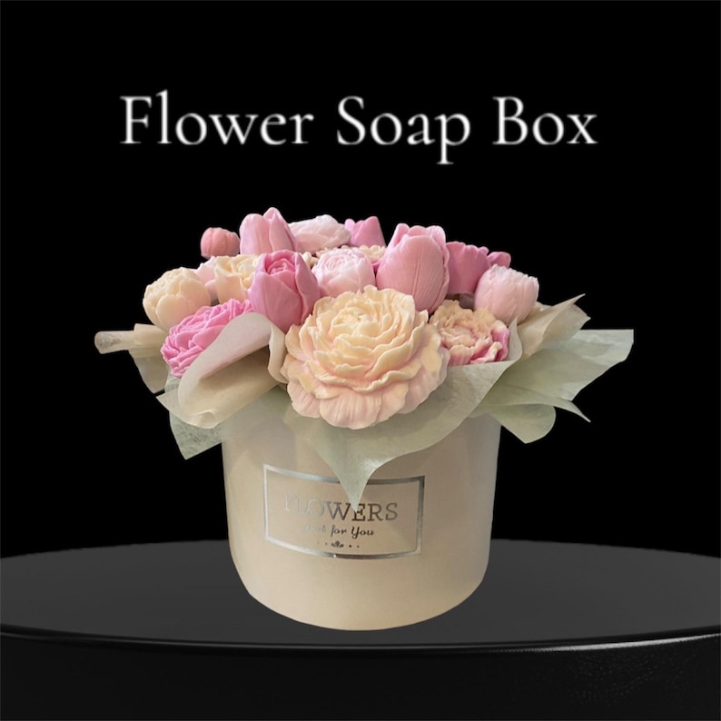 Puede incluir: Un ramo de flores de jab&oacute;n rosa y crema dispuestas en una caja redonda con fondo blanco y el texto "Flowers Just for You".