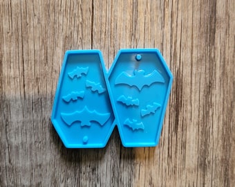 May include: Blue silicone mold shaped like a coffin with multiple bat silhouettes inside. The mold is designed for making resin crafts.