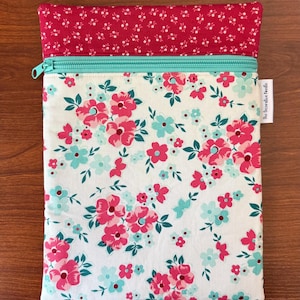 Puede incluir: Una bolsa con estampado floral y cremallera turquesa. La bolsa presenta un fondo blanco con flores rosas y turquesas. La secci&oacute;n superior es roja lisa con un estampado floral blanco. El texto "the decorative needle" est&aacute; impreso en el lateral.